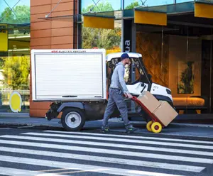 Postbote auf der Straße mit elektrischem Arbeitsfahrzeug im Hintergrund