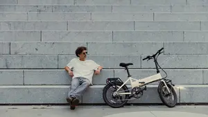 Person sitzt auf grauen Treppen neben einem E-Bike der Marke MATE