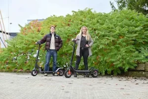 Ein Mädchen und ein Junge fahren im grünen Park mit E-Rollern – modernes Fahren erleben mit E-Mobilität & Fahrzeuge für Freizeit und Alltag.
