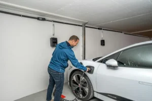 Mann lädt sein Elektroauto in der Garage mit Typ-2-Ladekabel – E-Auto laden zu Hause