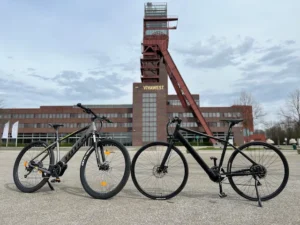 Zwei TOTEM E-Bikes vor einem industriellen Zechengebäude – leistungsstarke E-Bikes für Alltag, Stadtverkehr und Pendler.