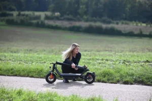 Mädchen transportiert zusammengeklappten Velix E-City Roller in grüner Natur – leichte, flexible und nachhaltige Mobilität