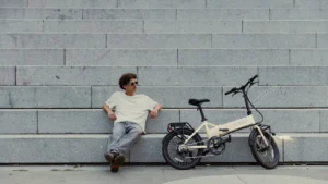 Person sitzt auf grauen Treppen neben einem E-Bike der Marke MATE