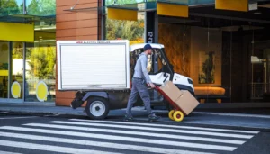 Postbote auf der Straße mit elektrischem Arbeitsfahrzeug im Hintergrund