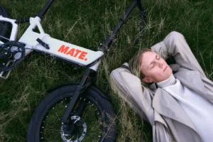 Ein Mann liegt entspannt auf grünem Gras neben seinem E-Bike und genießt eine Pause in der Natur